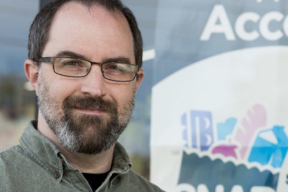 photo of man in front of sign in store window